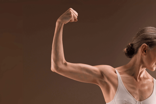 A strong and toned woman flexing her arm to display muscle definition, symbolizing the benefits of strength and fitness associated with Arcwell Creatine Monohydrate